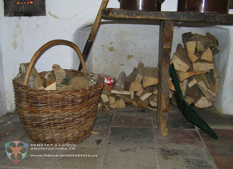 Palivové dřevo v proutěném koši a výklenku pod sporákem, obec Hoslovice, okres Strakonice